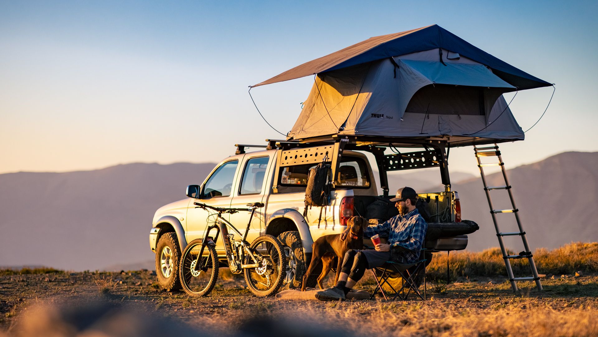 Pick up con carpa de techo Thule y bicicleta de montaña al atardecer