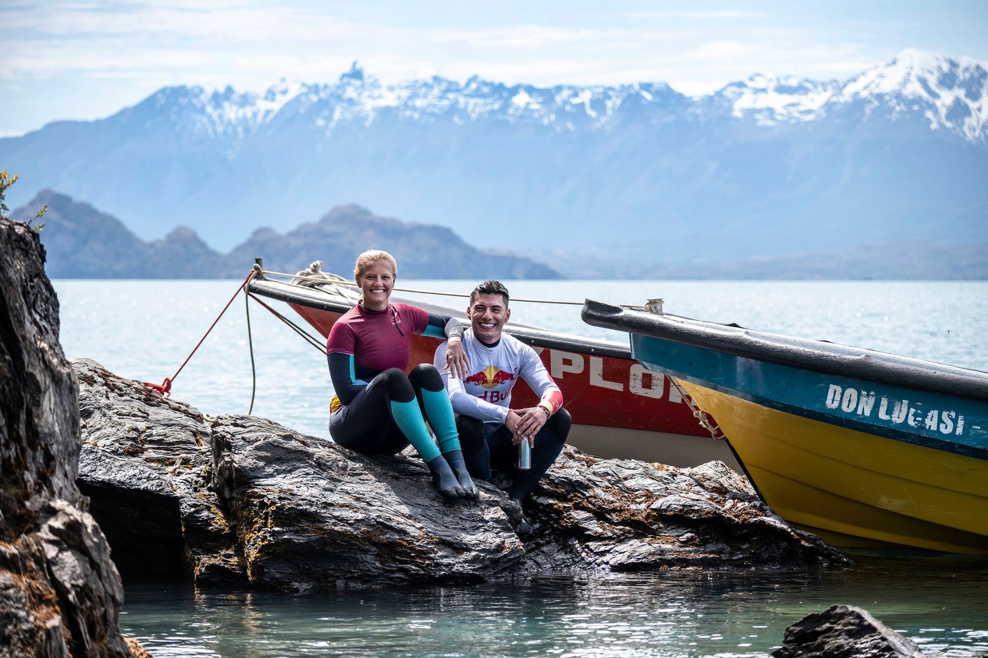 Atletas de Red Bull sentados frente a un lago y cordillera nevada